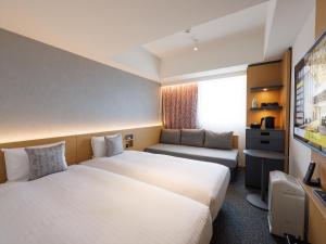 福冈CROSS Life Hakata Yanagibashi的一间酒店客房,设有两张床和电视