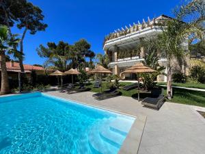 皮诺港Villa Aquamarina Pavoncella Rossa的一座带遮阳伞的建筑前的游泳池