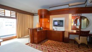 万隆Hotel Savoy Homann的酒店客房配有一张床、一张书桌和一台电视。