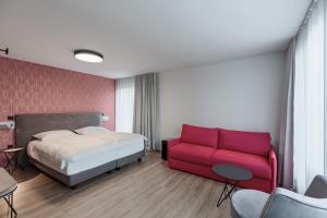 卢布尔雅那ibis Styles Ljubljana Centre的一间卧室配有一张床和一张红色的沙发