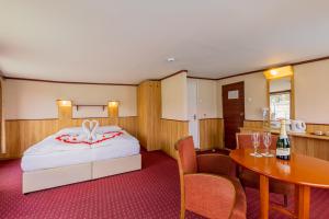 布达佩斯Fortuna Boat Hotel Budapest的一间卧室配有一张床和一张桌子及一瓶葡萄酒