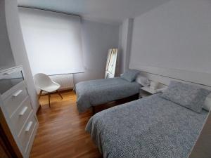 米尼奥Adiva Praia Miño的小房间设有两张床和椅子