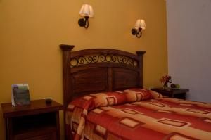 库斯科麦奎旅馆的卧室配有一张床,墙上有两盏灯