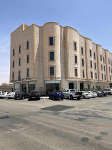 哈伊勒فندق سكناي الياسمين的停车场内停放汽车的大型建筑