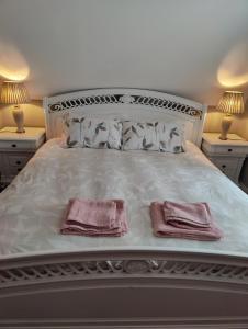 ManorhamiltonMaggies Cottage的一张白色的床,上面有两条粉红色的毛巾