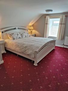 ManorhamiltonMaggies Cottage的卧室配有一张白色大床和红地毯
