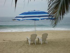 派德拉库耶斯塔Condominio Gaudi的海滩上一把遮阳伞下的两把椅子