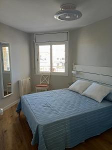 拉皮内达SEAFRONT APARTMENT PINEDA BEACH的一间卧室设有蓝色的床和2个窗户。