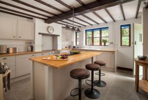 Combe Saint NicholasSmithycroft的厨房配有白色橱柜和带酒吧凳的木制岛屿