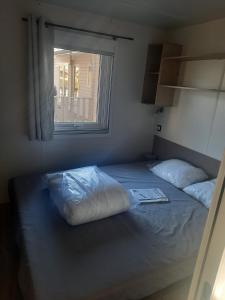 纳博讷Charmant mobil-home 178的一间卧室配有带两个枕头的床和窗户