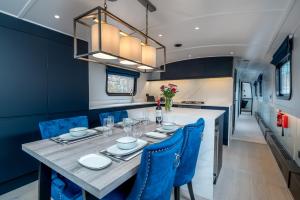 伦敦JOIVY Elegant houseboat near Canary Wharf的一间带桌子和蓝色椅子的用餐室