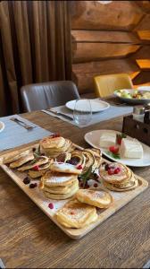 巴尼亚Alpina Luxury Chalets的木桌上的薄煎饼托盘