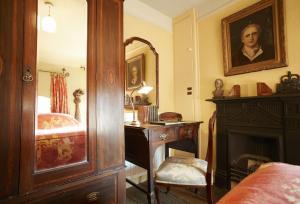 内瑟·斯托威Toll House的一间卧室配有书桌、一张床和镜子