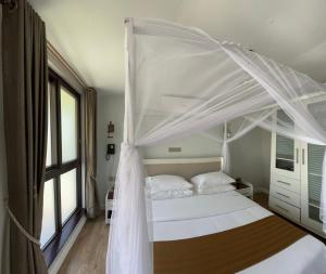 HoimaZebi Ecolodge的一间卧室配有一张带天蓬的白色床