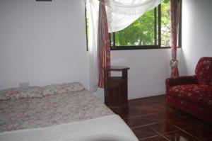 马埃岛木瓜别墅的卧室配有床、椅子和窗户。
