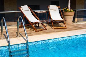卡利塞亚-豪客迪克斯Vellum Luxury Living的游泳池畔的两把椅子和一张桌子