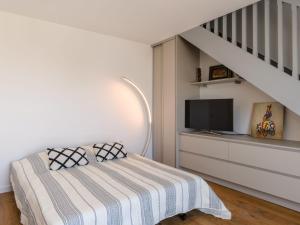 阿卡雄Apartment Claire-4 by Interhome的一间卧室设有一张配有电视的床和楼梯。