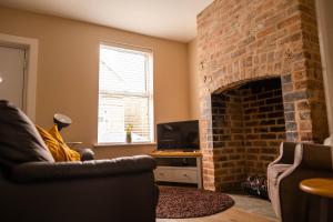 什鲁斯伯里Rose Cottage的客厅设有砖砌壁炉和沙发。