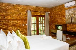 比勒陀利亚Mela Luxury Game Lodge的一间卧室设有两张床和砖墙