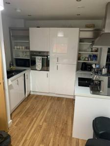 利物浦Liverpool City Centre Apartment的厨房铺有木地板,配有白色橱柜。