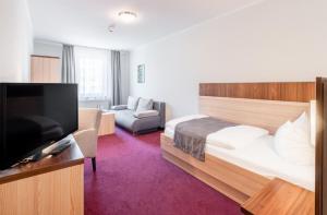 诺伊鲁平诺伊鲁平运动酒店的配有一张床和一台平面电视的酒店客房