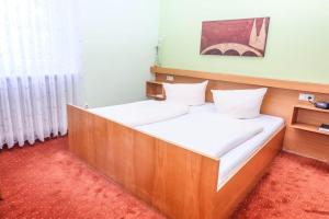 雷根斯堡维纳特餐厅酒店的一间卧室配有一张带白色床单的木床