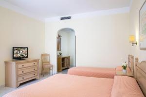 奥罗塞伊玛丽娅罗萨日亚酒店的一间卧室配有两张床、一台电视和一个梳妆台。
