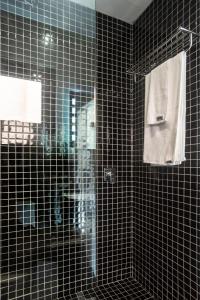 迪亚尼海滩Boxo Diani - Unique Beach Front Container Eco-Hotel的带淋浴和镜子的黑色瓷砖浴室