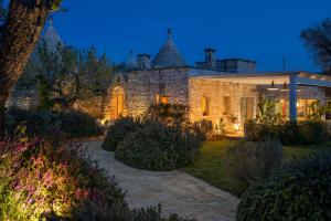 奥斯图尼Ostuni Art Resort的一座大型石头房子,晚上设有花园