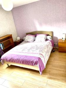 鲁昂80m2-Maison des quais - parking - jardinet的一间卧室配有一张带紫色棉被的床