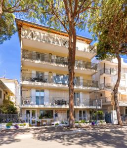 里乔内Residenza Clelia Riccione的公寓大楼设有阳台和树木