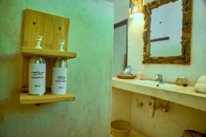 瓦塔穆Mvuvi Lodge的浴室位于水槽旁的架子上,配有2瓶除臭剂