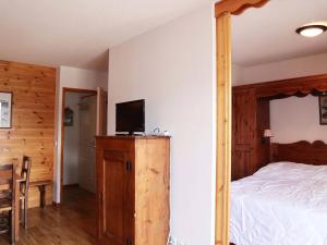 莱索尔Appartement Les Orres, 3 pièces, 8 personnes - FR-1-322-325的一间卧室配有一张床,木制橱柜上配有电视