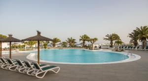 卡门港ILUNION Costa Sal Lanzarote的一个带椅子和棕榈树的度假村游泳池