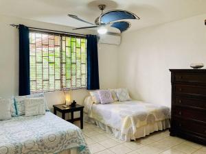 雅科La Mona Beach House的一间卧室设有两张床、一个梳妆台和窗户。