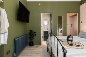 伯恩茅斯Stylish Central Apartment的一间卧室设有绿色的墙壁、一张床和一个浴缸