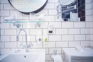 巴斯阿可仑普拉特酒店的白色瓷砖浴室设有水槽和卫生间