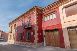 特鲁埃尔Barranco de las Maravillas的红色的建筑,设有门和阳台
