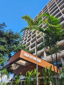 檀香山Wayfinder Waikiki的棕榈树前有标志的建筑