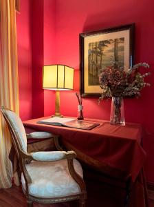 托莱多阿尔穆尼亚德善秘古尔酒店的红色的房间,配有桌子、灯和椅子