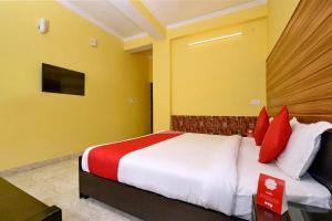 德拉敦OYO Flagship Maira Residency的一间卧室配有红色和白色枕头的床
