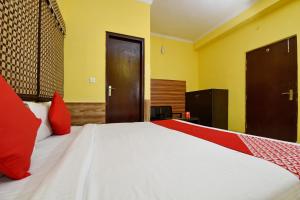 德拉敦OYO Flagship Maira Residency的卧室配有带红色枕头的大型白色床