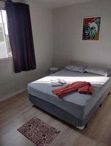 蓬塔格罗萨Apartamento novo wi-fi + TV的一间卧室配有一张带红色毛巾的床