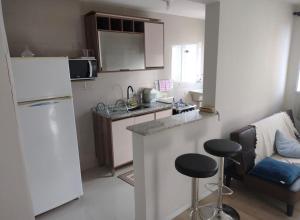 蓬塔格罗萨Apartamento novo wi-fi + TV的带冰箱、柜台和凳子的小厨房