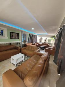 JiduDazzle Hotels and Apartments的客厅配有棕色皮沙发和白色桌子