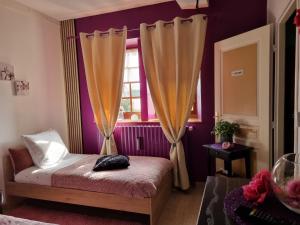 Le TrembloisChez Martine et Laurent的一间卧室设有紫色的墙壁和一张带窗户的床