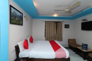 RāmpuraOYO 13161 Apni Havali Hotel & Restaurant的卧室配有带红色枕头的白色床