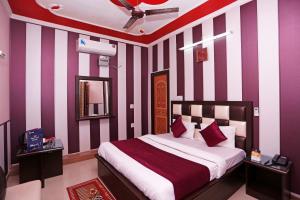 JwālāpurMehfil Hotel的一间卧室配有一张紫色和白色条纹的床