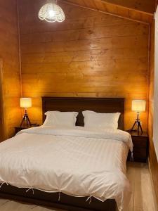 Khalij Salmanأكواخ وشاليهات باشن الريفية的一间卧室配有一张带两盏灯的大型白色床。