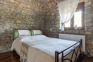 Πέτρινη εξοχική κατοικία, Λάρισα的卧室配有一张石墙床